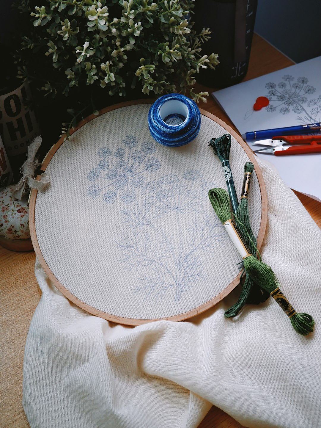 Embroidery hoop and crafting supplies arranged on a wooden table.