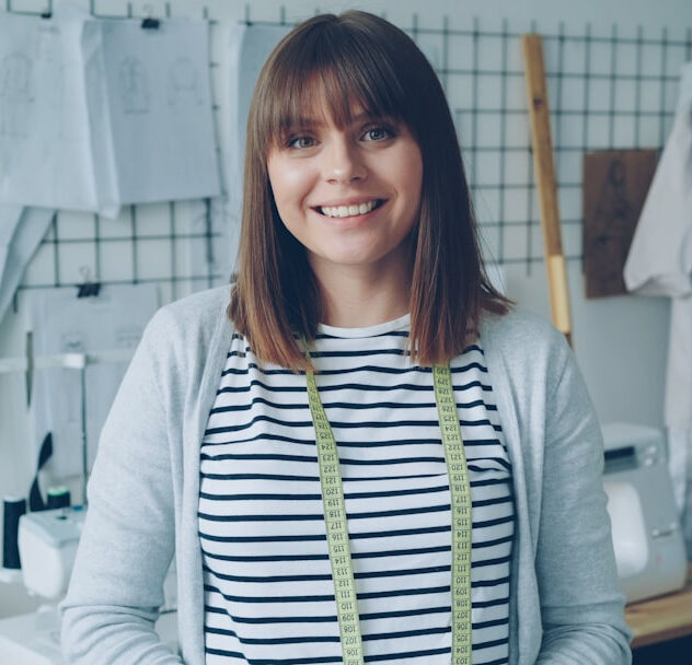 Fashion designer smiling in her creative sewing workshop.
